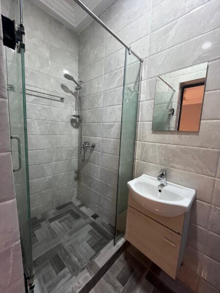 Modern bathroom with a walk-in glass shower, ceramic tiles, and floating vanity sink.