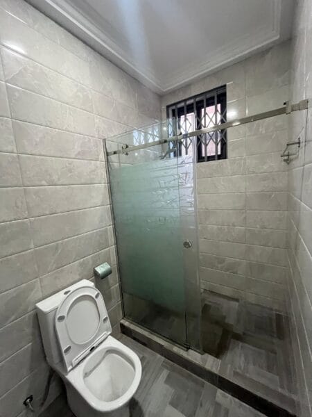 Modern bathroom with a walk-in glass shower, ceramic tiles, and floating vanity sink.