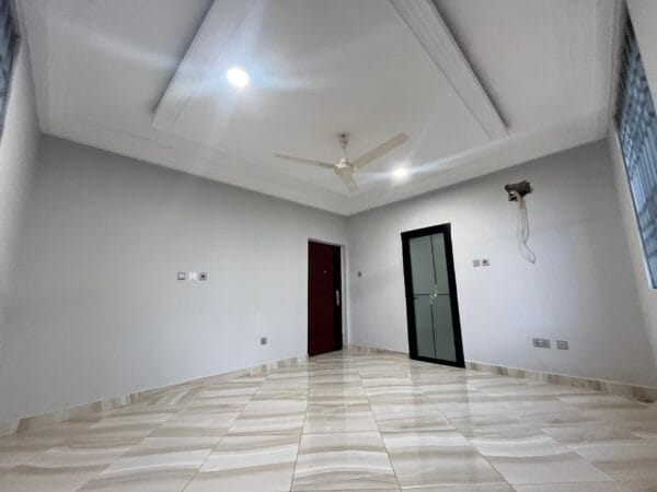 Bedroom with large windows, ceiling fan, and neutral wall tones, leading to an ensuite bathroom