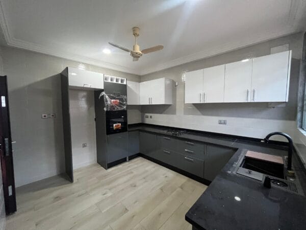Fully fitted kitchen with modern cabinetry, oven, gas stove, and black countertops.