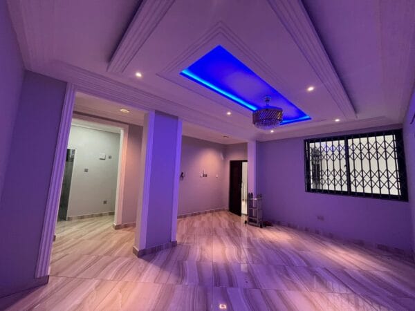 Large living room with recessed lighting and blue ceiling accents, chandelier, and polished marble-effect flooring.