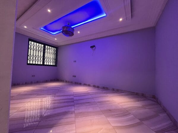 Large living room with recessed lighting and blue ceiling accents, chandelier, and polished marble-effect flooring.