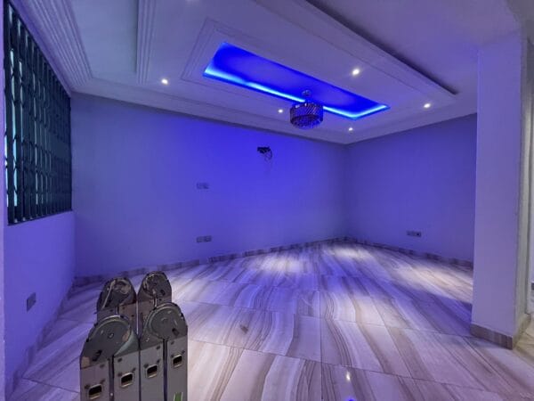Large living room with recessed lighting and blue ceiling accents, chandelier, and polished marble-effect flooring.