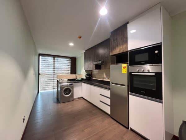 Modern kitchen with dark wood accents, stainless steel appliances, and dining table for four.