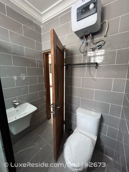 Clean and functional bathroom design featuring modern fittings and a water heater for your convenience.