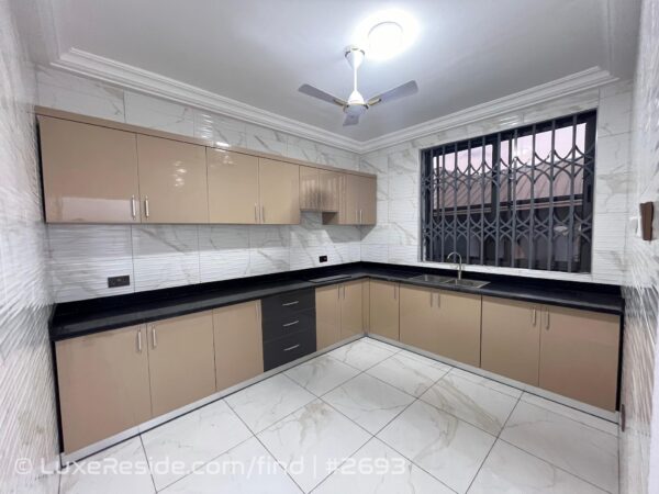 Spacious and well-lit kitchen with ample cabinetry and a wide window for natural light.
