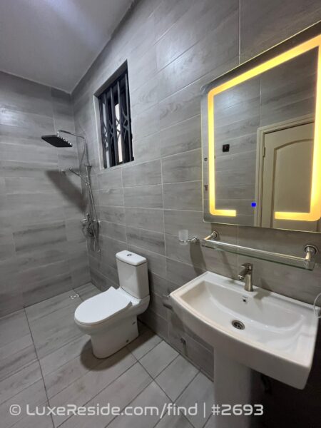 Rainfall shower head above tiled shower space with modern WC and security window