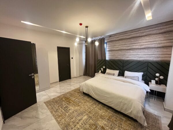 Luxurious master bedroom bedroom with a king-sized bed, mounted TV, and plush headboard.