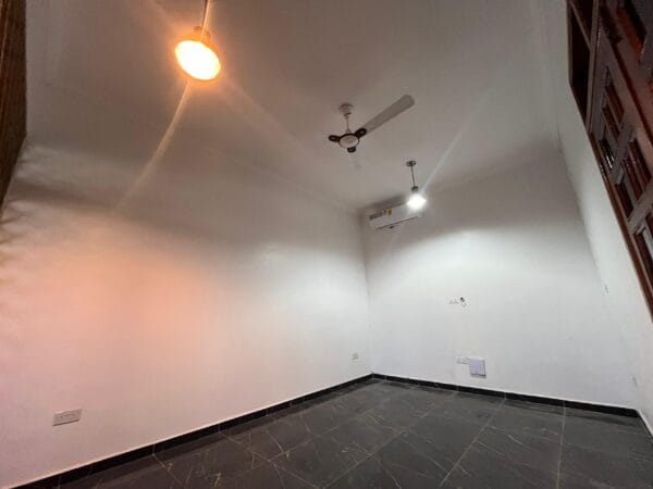 Well-lit living room with marble floors, a ceiling fan, and air conditioning.