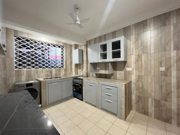 Fully equipped kitchen with cabinets, stove, and a double sink.