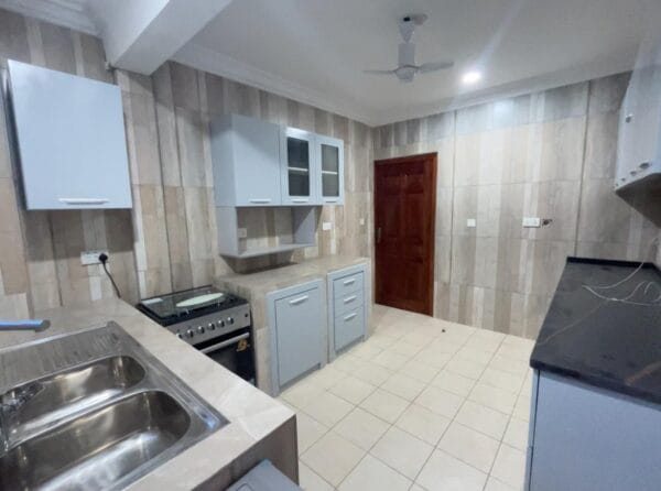 Fully equipped kitchen with cabinets, stove, and a double sink.