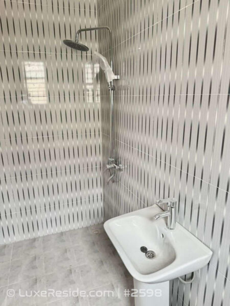 Contemporary bathroom featuring a walk-in shower with a rain showerhead, modern sink, and attractive tiled walls.