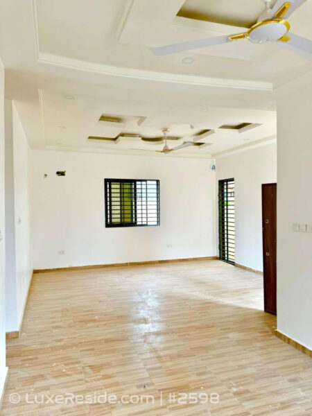 Bright, airy bedroom with tiled floors, ceiling fan, and secure window grille.