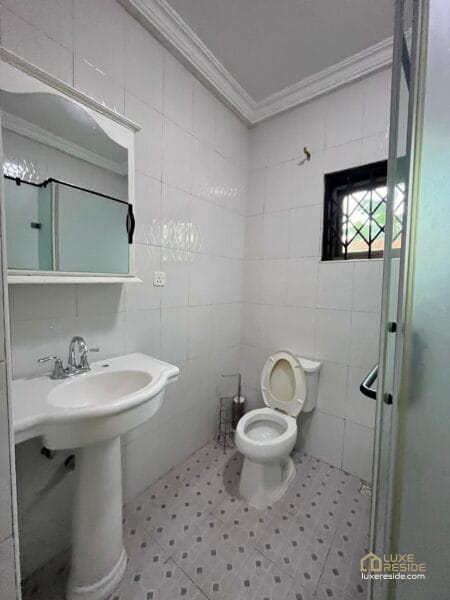 Bathroom with sink, toilet, and a window with security bars.