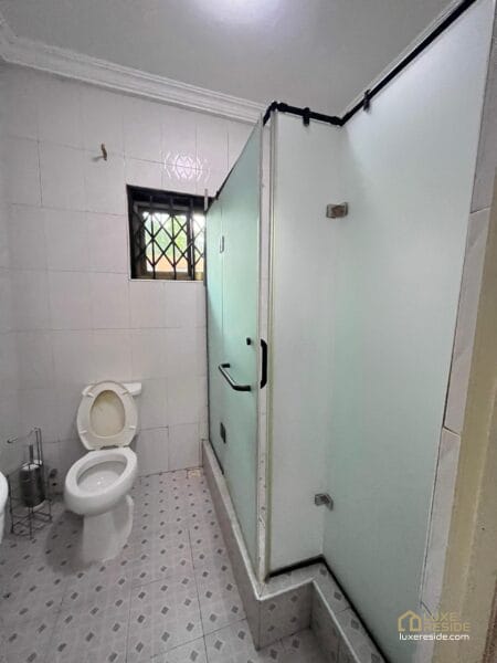 Bathroom with sink, toilet, and a window with security bars.