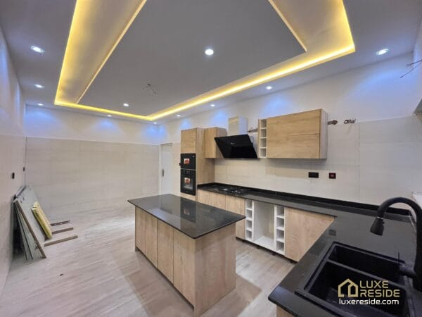 Modern kitchen with an island, built-in appliances, and warm ceiling lighting.