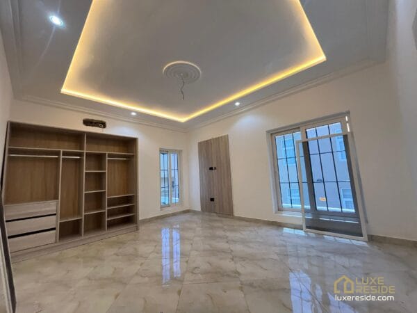 Spacious bedroom with built-in wardrobe, large windows, and recessed ceiling lights.