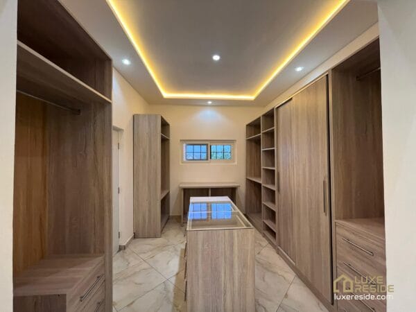 Walk-in closet with modern wooden shelving and soft lighting.