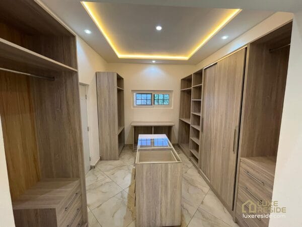 Walk-in closet with modern wooden shelving and soft lighting.