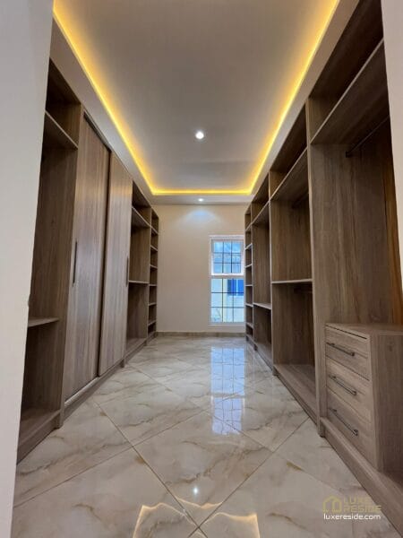 Walk-in closet with modern wooden shelving and soft lighting.