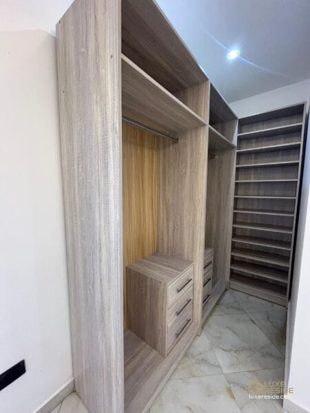 Walk-in closet with modern wooden shelving and soft lighting.