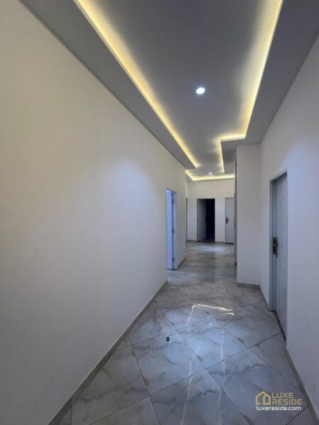 Spacious hallway with polished tile floors and elegant lighting.