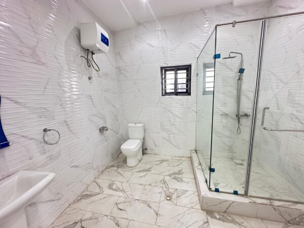 Elegant bathroom with marble-effect tiles and a walk-in glass shower.