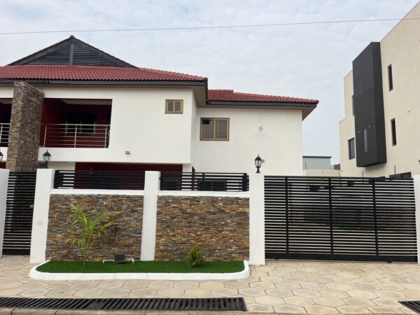 Exterior view of a two-story house with paved courtyard and small garden area.
