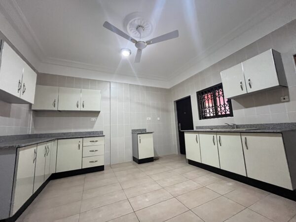 Large kitchen with plenty of cabinet space and tiled floors.