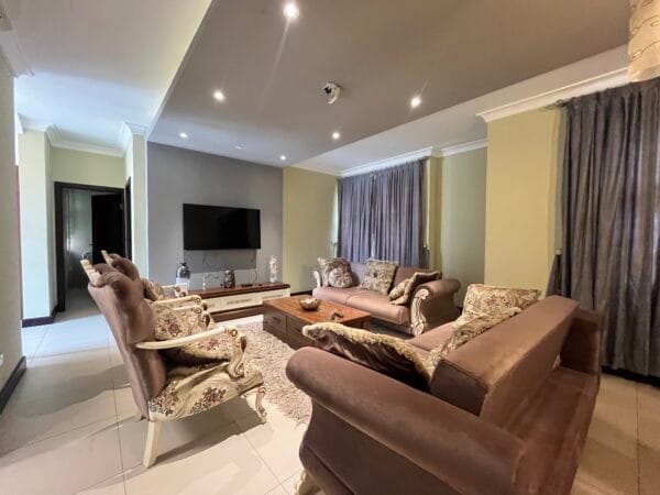 Elegant living room with plush sofas, large TV, and neutral decor.