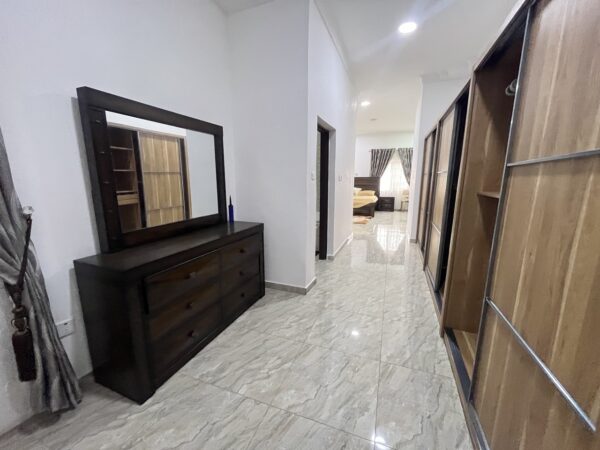 Walk-in closet area with dresser and wooden wardrobes.