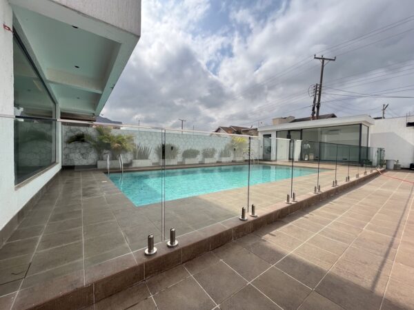 Large private pool with glass fencing and a pool house with separate facilities.