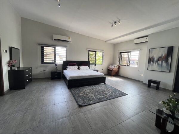 Large master bedroom with plenty of natural light and modern decor.