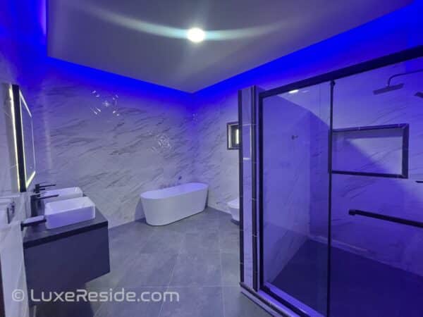 Luxurious bathroom with marble walls, a soaking tub, and LED mirror