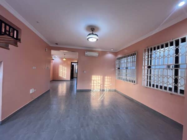 Spacious living room with windows allowing plenty of natural light and tiled flooring.