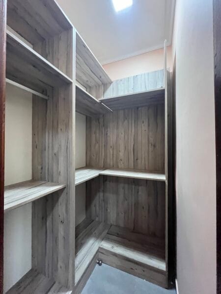 Walk-in closet with built-in wooden shelving and ample storage space.