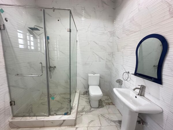 Elegant bathroom with marble-effect tiles and a walk-in glass shower.