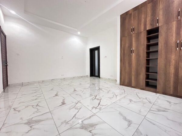 Spacious bedroom with built-in wooden wardrobes and modern tile flooring.